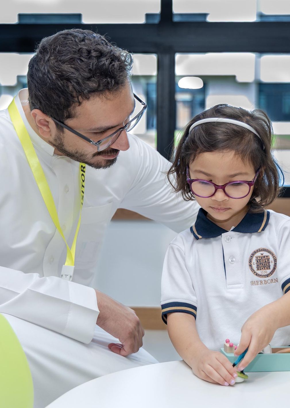 Sherborne School Jeddah teacher helping a student to create a playdough sculpture.