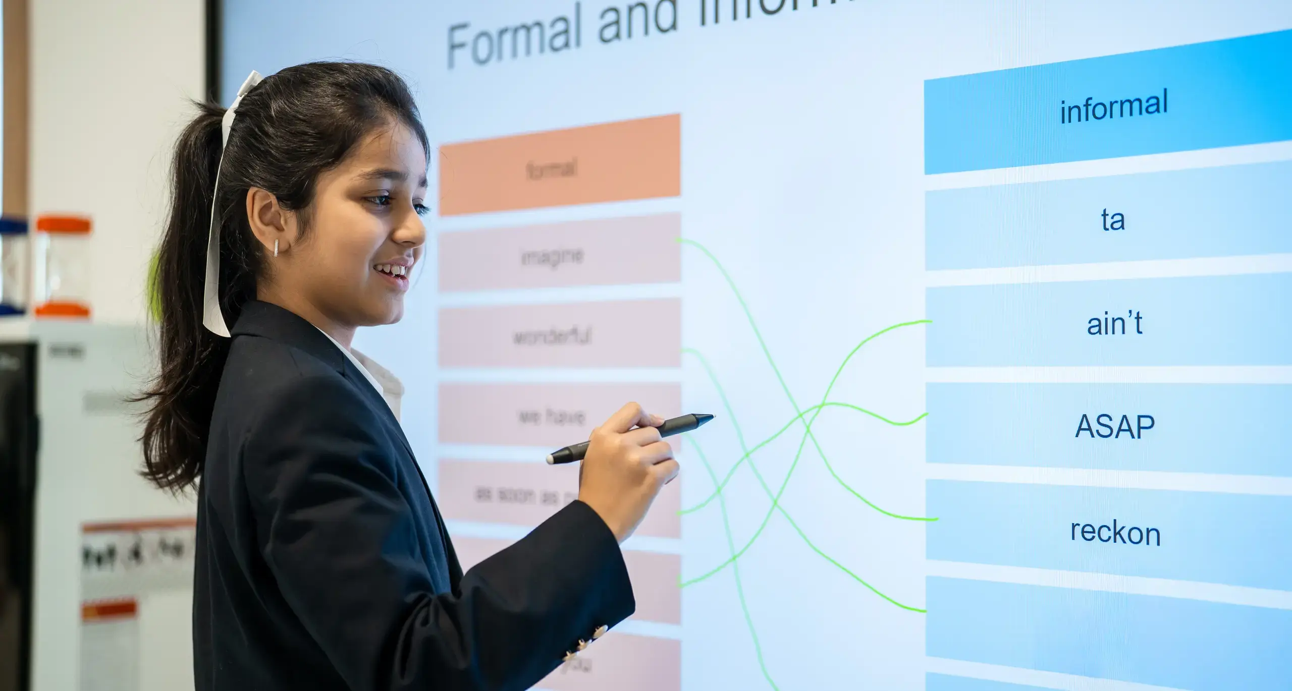 Sherborne School Jeddah student matching up formal and informal words and phrases on an interactive whiteboard.