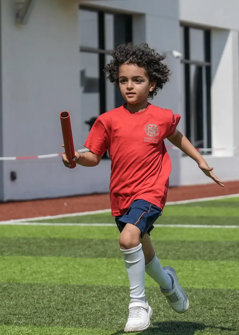 Sherborne School Jeddah student running a relay on sports day.