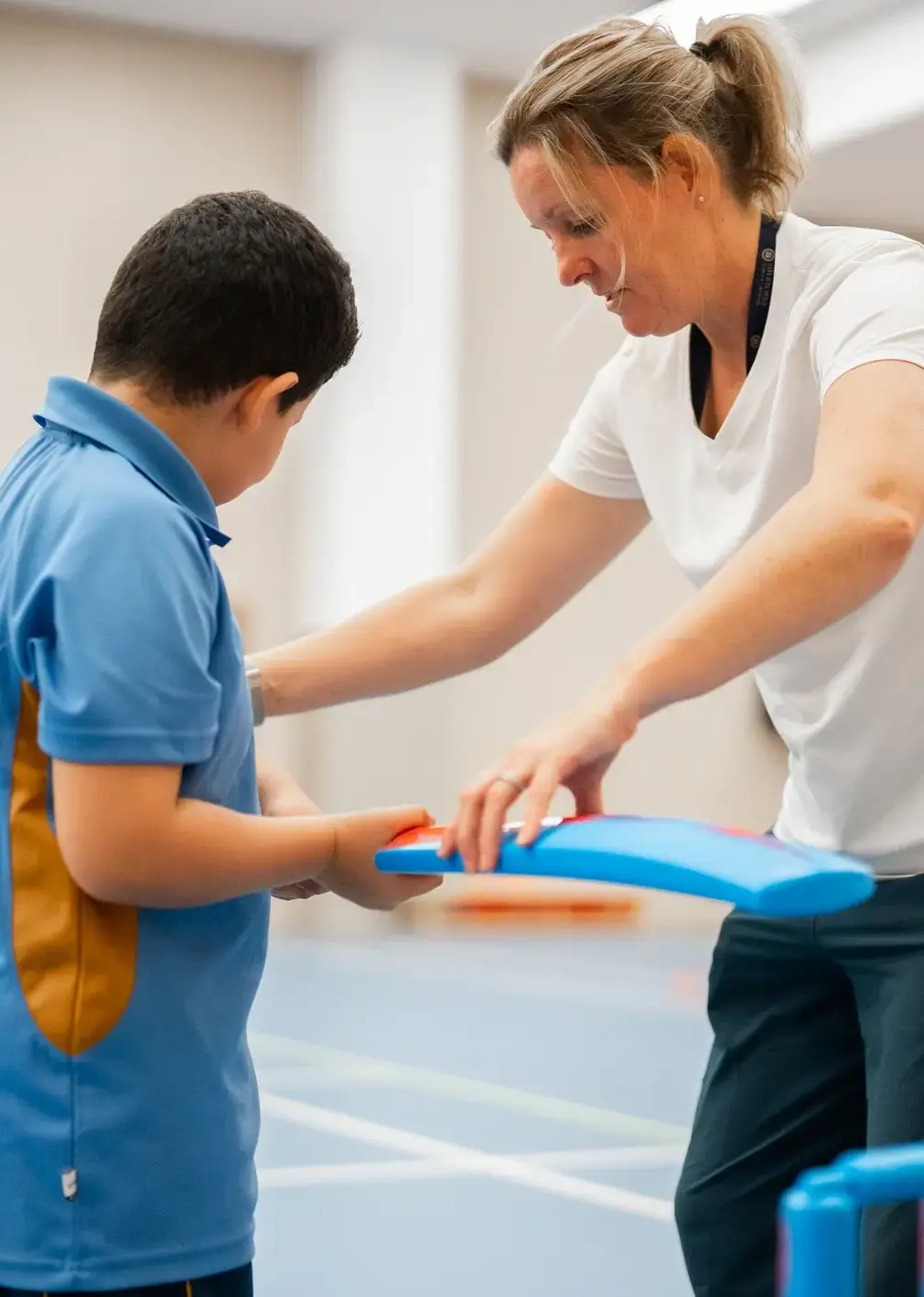 Sherborne School Jeddah sports teacher showing a student how to hold a cricket bat.