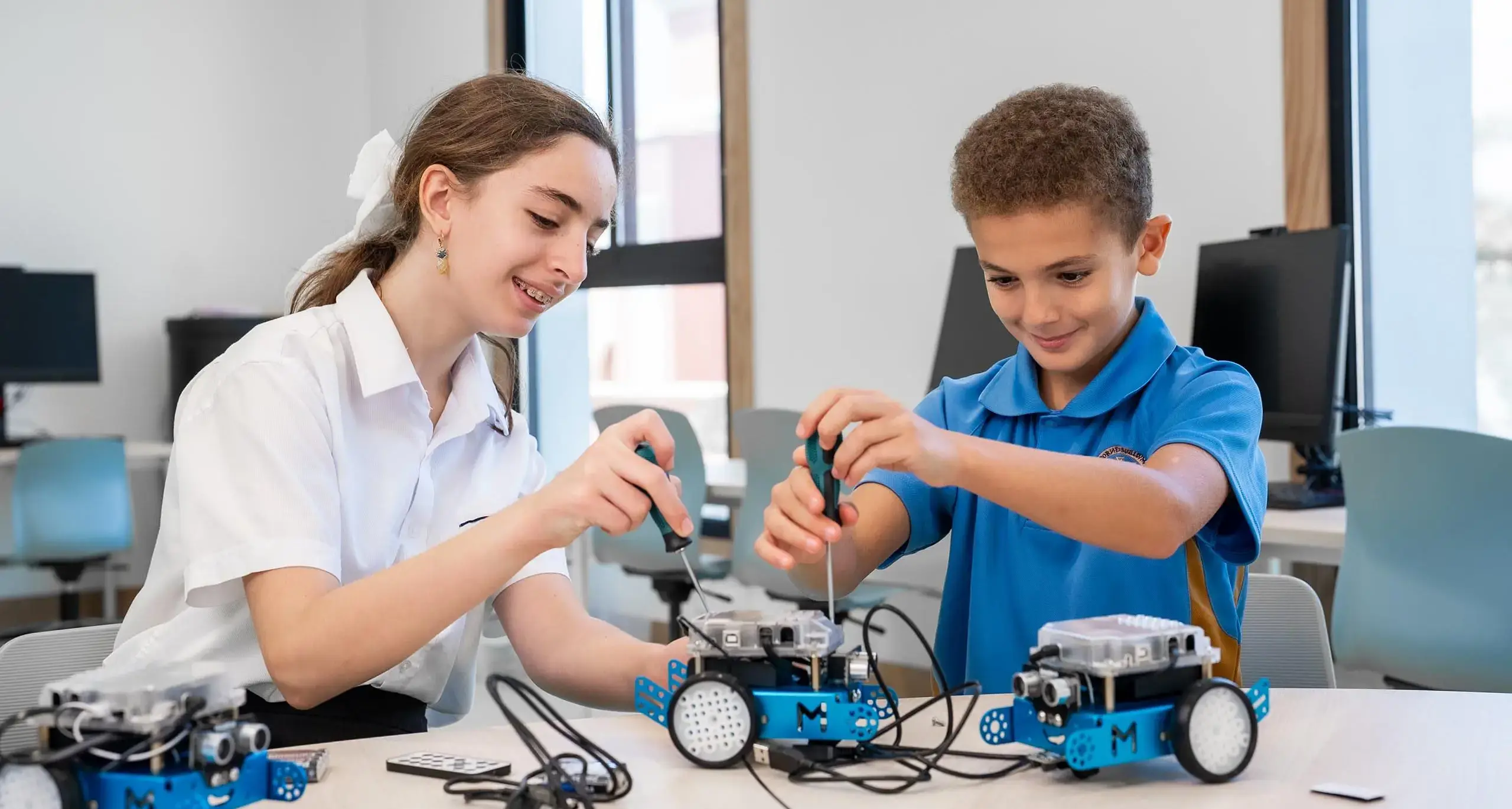 Sherborne School Jeddah students tinkering with robotic cars in a robotics lesson.
