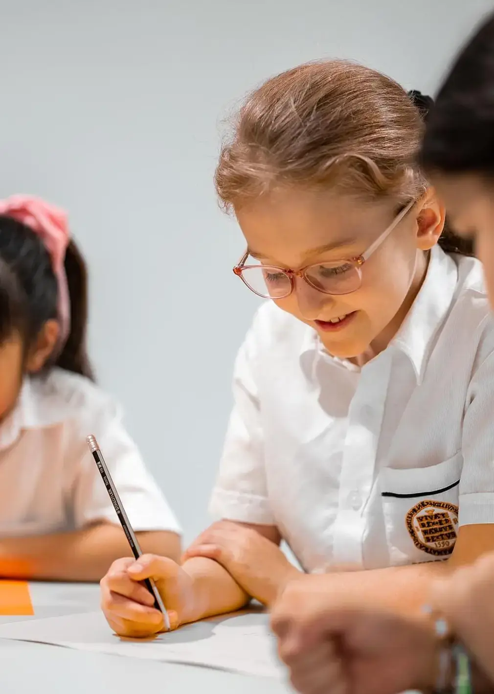 Students sitting at a desk writing during an English lesson