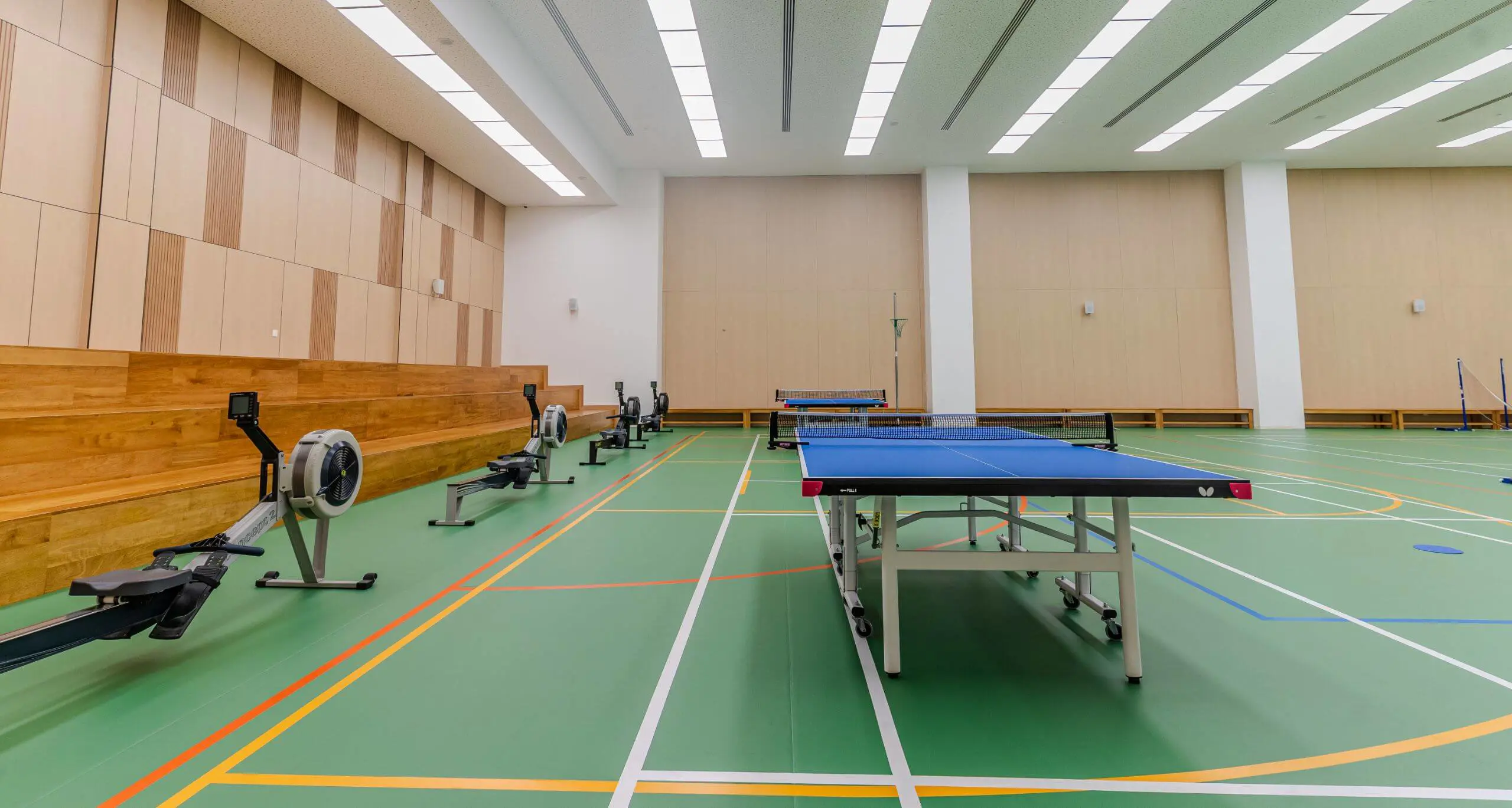 Sherborne School Jeddah Sports Hall with a netball hoop, rowing machines, and table tennis tables.