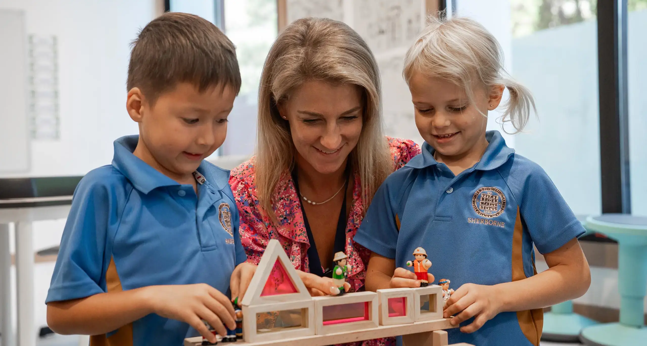 Sherborne School Jeddah teacher helping students build with wooden blocks.